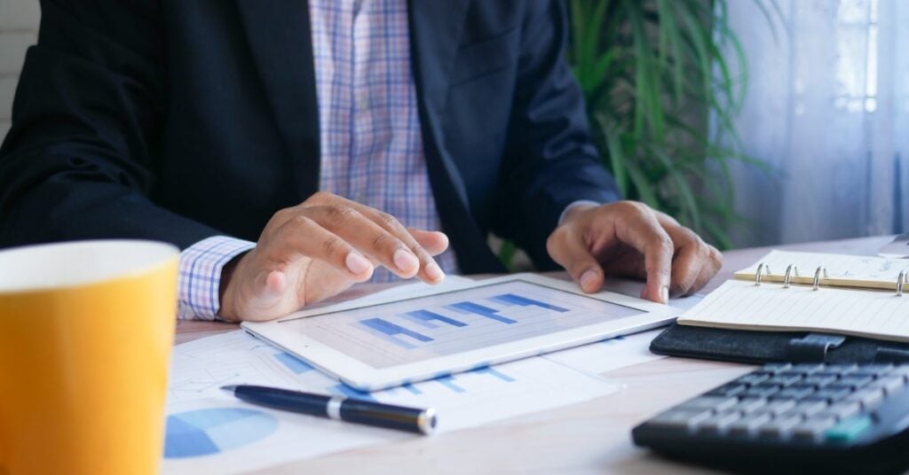 Man on a tablet looking at bar graphs.